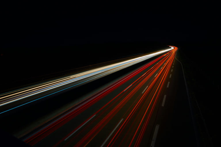 Autobahn bei Nacht mit verschwommenen Lichtspuren als Metapher für schnelles und leistungsstarkes Managed Hosting für WordPress-Websites.