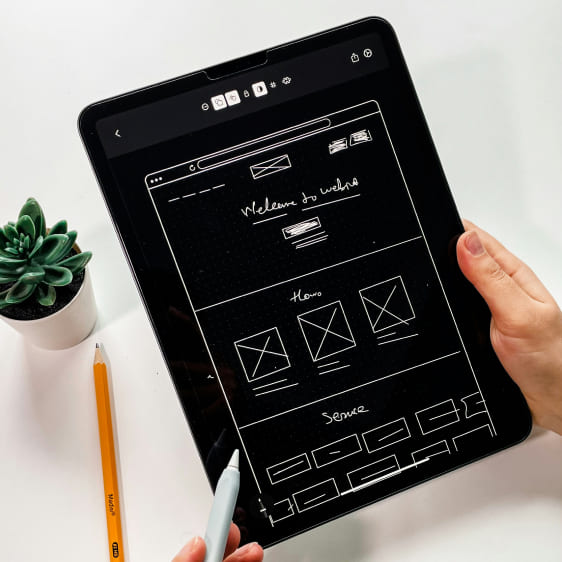 Eine Person, die mit einem Stylus eine Webseiten-Skizze auf einem Tablet entwirft.