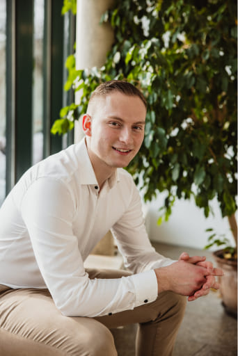 Der Inhaber von Lechner IT-Dienstleistungen, Tobias Lechner, sitzt in einem hellen und modernen Büro neben einer Pflanze.