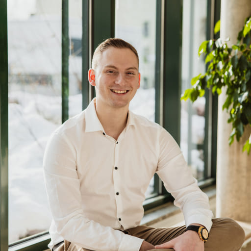 Tobias Lechner, der Inhaber von Lechner IT-Dienstleistungen, sitzt in einem weißen Hemd vor einem Fenster mit Blick auf den Schnee.