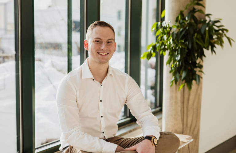 Tobias Lechner von Lechner IT-Dienstleistungen sitzt lächelnd in einem weißen Hemd am Fenster.